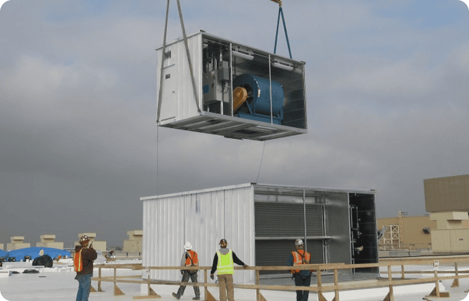 Crane lifting HVAC unit onto rooftop.