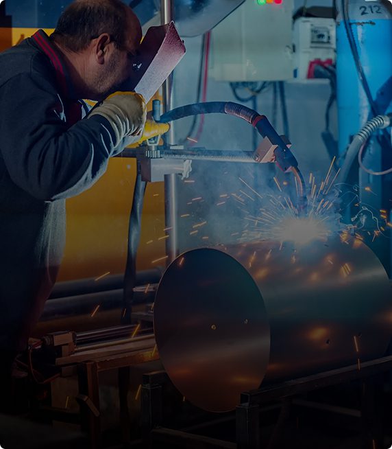 Worker welding metal with safety gear.